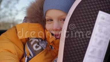 小男孩坐在儿童安全座椅上，穿着冬天的夹克。